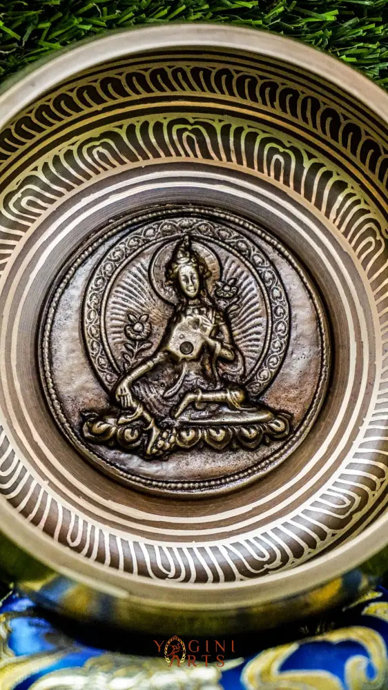 A beautifully carved singing bowl featuring the Green Tara deity at its center, surrounded by Om Mani Padme Hum inscriptions. This bowl produces a rich, resonant tone that supports meditation and spiritual practice. Green Tara symbolizes compassion, swift healing, and protection. Ideal for deepening your meditation practice, enhancing your altar space, or creating moments of inner peace and clarity.