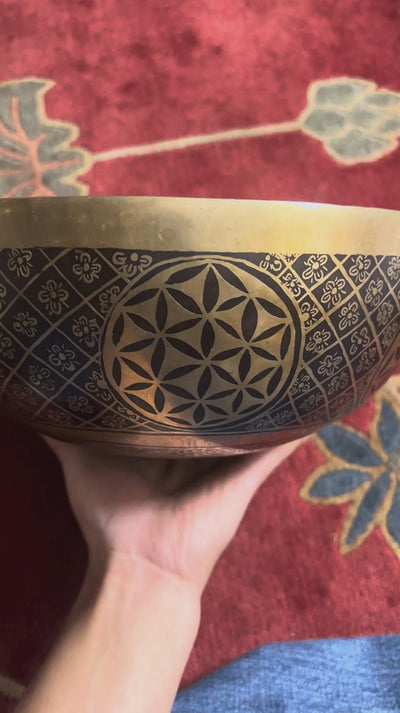 Golden Chengresi Tibetan singing bowl featuring sacred Buddhist engravings and geometric floral designs on a pink brocade cushion.