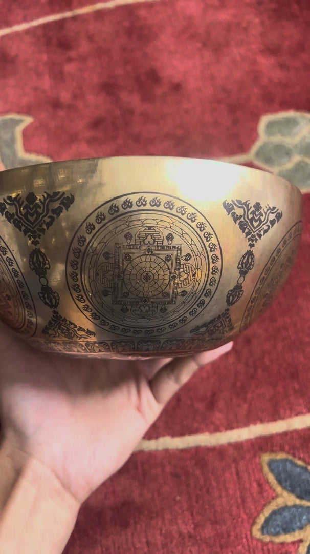 Load video: Engraved Om Mani Padme Hum Mandala Singing Bowl displayed upright with a wooden mallet and blue cushion.