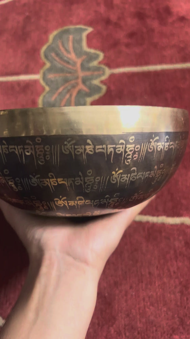 Detail of the sacred Om symbol and circular mantra engravings inside a traditional Himalayan inspired singing bowl.