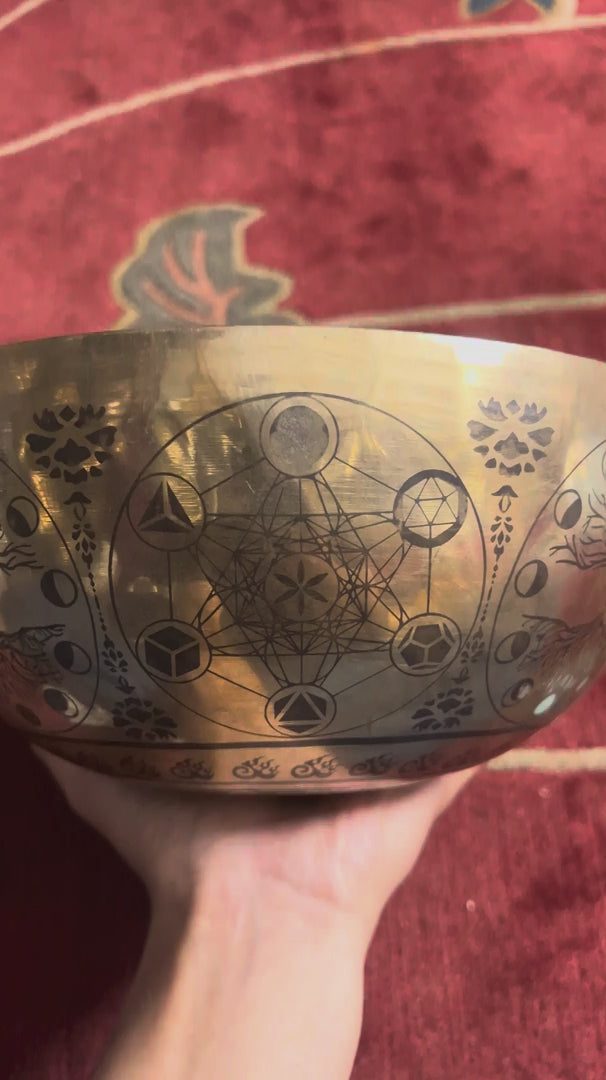 Universe singing bowl shown upright with a wooden mallet and pink cushion, featuring detailed celestial engravings inside.