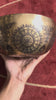 Floral Mandala singing bowl standing upright on a blue cushion beside a wooden mallet, showcasing its engraved interior design.