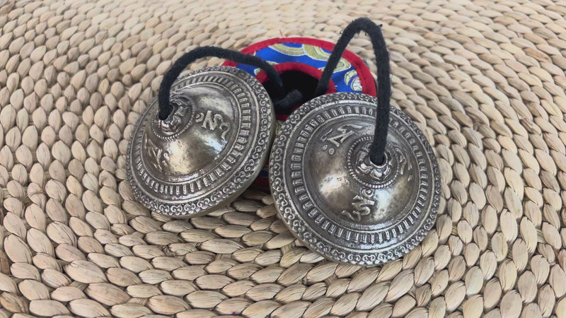 Close up of Tibetan Lotus Tingsha Cymbals showing detailed circular borders and traditional engraved symbols.