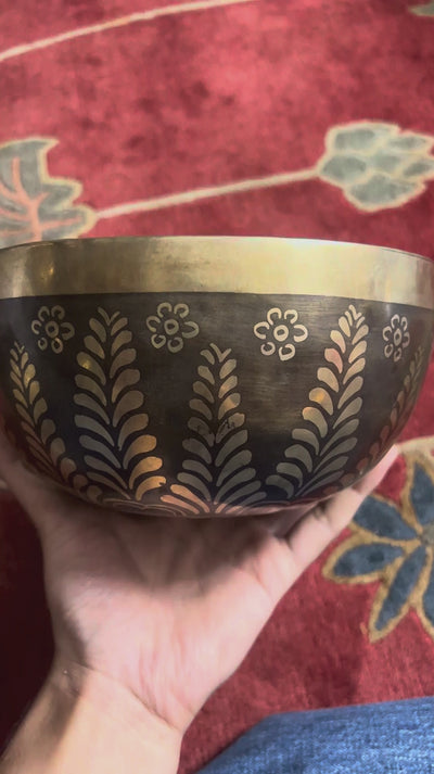 Flower Yin Yang singing bowl displayed upright with a wooden mallet and blue brocade cushion, showing the engraved interior design.