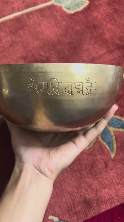 Close up of a detailed hand-engraved tiger motif with fine stippling inside a golden bronze Tibetan singing bowl.