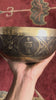 Conch shell engraved Tibetan singing bowl with dark bronze exterior and gold Tibetan script detailing.