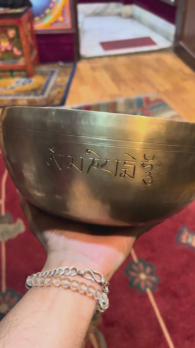 Handcrafted Tibetan singing bowl with engraved lotus flower design on the interior and blue decorative cushion