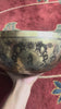 Green Tara bronze singing bowl displayed upright on a purple brocade cushion with two wooden handled mallets