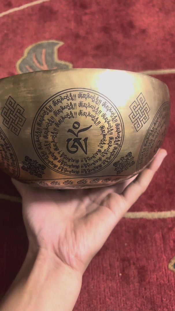 Load video: Medicine Buddha singing bowl shown upright with a wooden handled mallet and decorative engraving