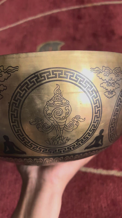 Buddha Mandala bronze singing bowl displayed upright on a purple brocade cushion with two mallets