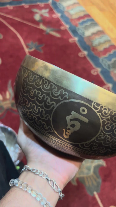 Handcrafted Flower of Life singing bowl from Nepal with sacred geometry engraving, Tibetan-style motifs, bronze-gold finish and blue cushion.