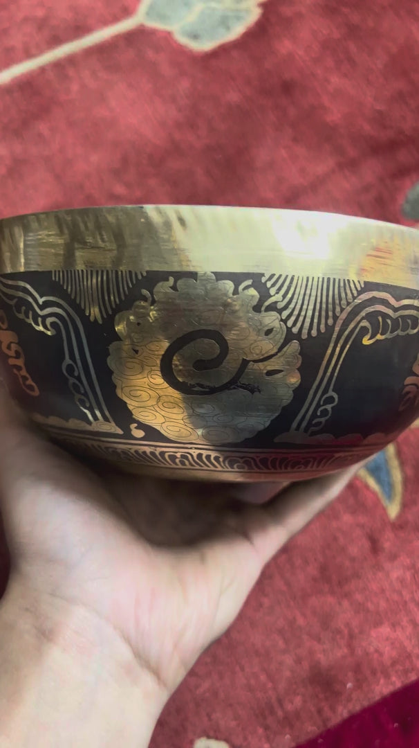 Load video: Hindu Om singing bowl standing upright with a wooden mallet and blue brocade cushion, showing the central Om engraving.