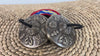 Angled view of a pair of Tibetan tingsha cymbals showing raised Buddhist motifs and decorative central details.