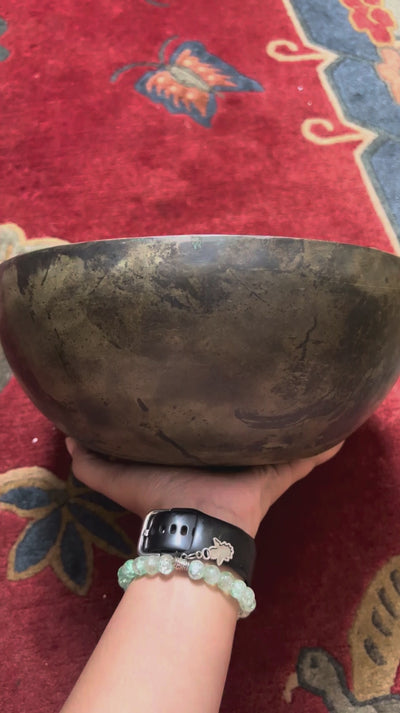Semi antique Tibetan singing bowl handmade in Nepal with aged bronze finish on a traditional blue cushion