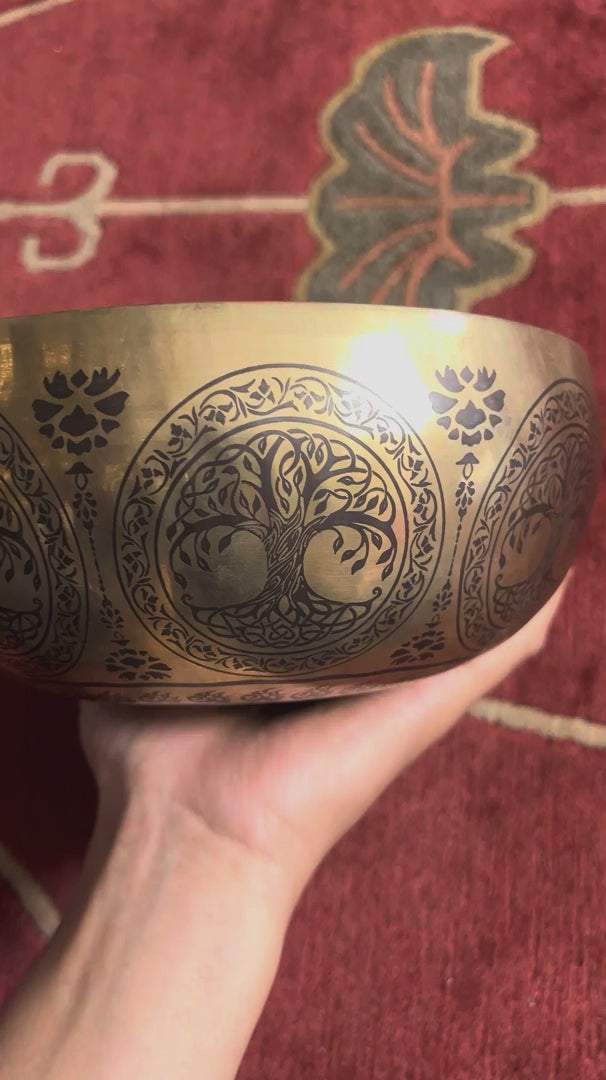 Tree of Life singing bowl shown upright on a blue cushion with a wooden mallet beside it.