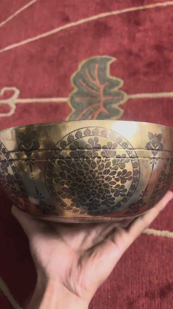 Cosmos engraved singing bowl displayed upright with a wooden mallet and blue cushion, showcasing its detailed geometric interior.