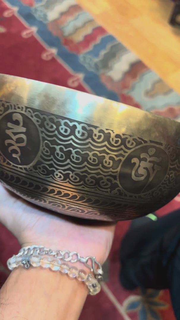 Handcrafted Flower of Life singing bowl from Nepal with sacred geometry engraving, Tibetan-style motifs, bronze-gold finish and blue cushion.