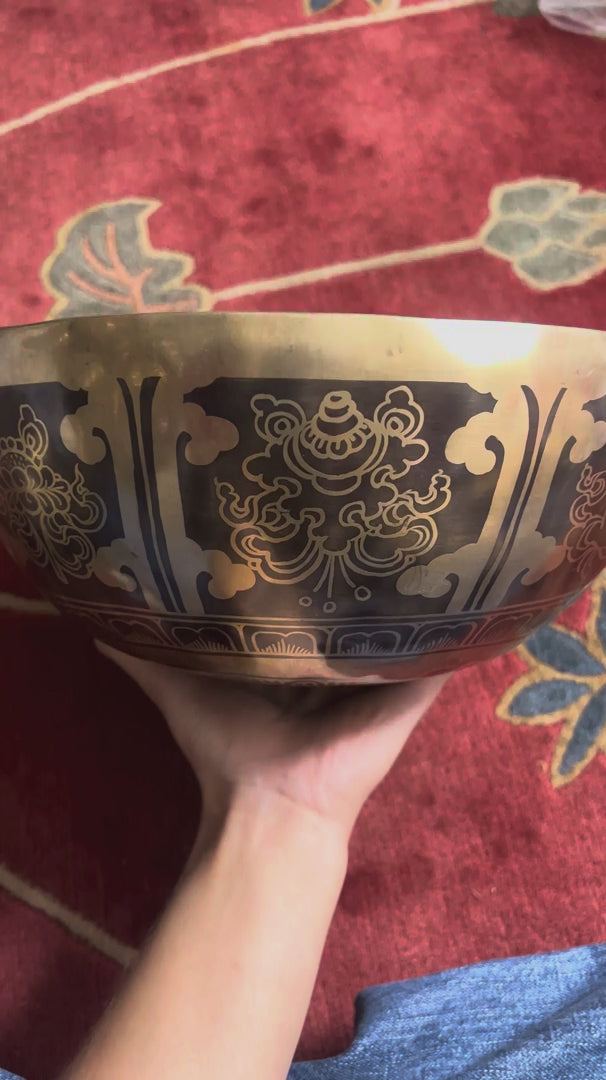 Buddha footprint singing bowl shown upright with wooden mallets and a pink brocade cushion, highlighting the traditional engraved design.