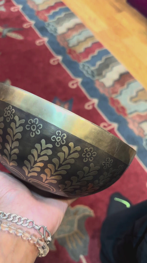 Handcrafted Yin Yang singing bowl from Nepal with floral engraving and bronze-gold finish for meditation and sound practice.