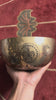 Turtle inspired engraved singing bowl displayed upright with a wooden mallet and blue cushion, showing the detailed interior artwork.