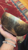 Handcrafted Tibetan singing bowl from Nepal with Buddhist symbol engraving, Tibetan-style script, bronze-gold finish, red cushion and wooden striker.